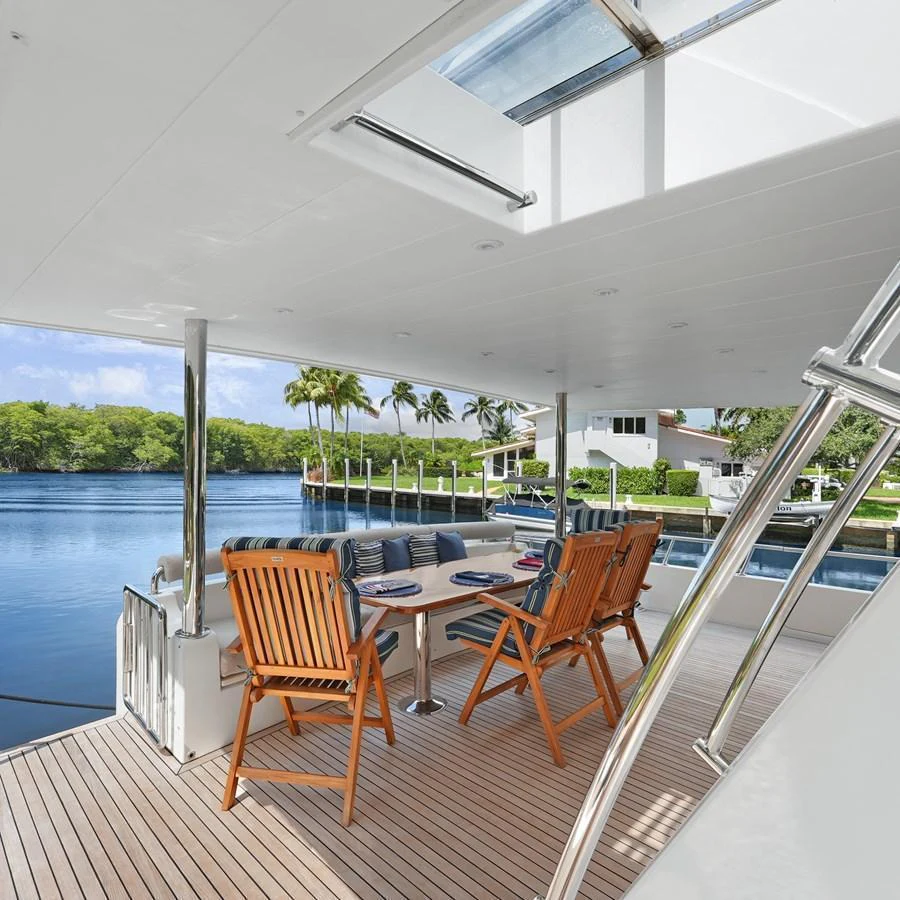 The aft deck offers a serene dining area with a picturesque waterfront view. aboard MILES AWEIGH Yacht for Sale