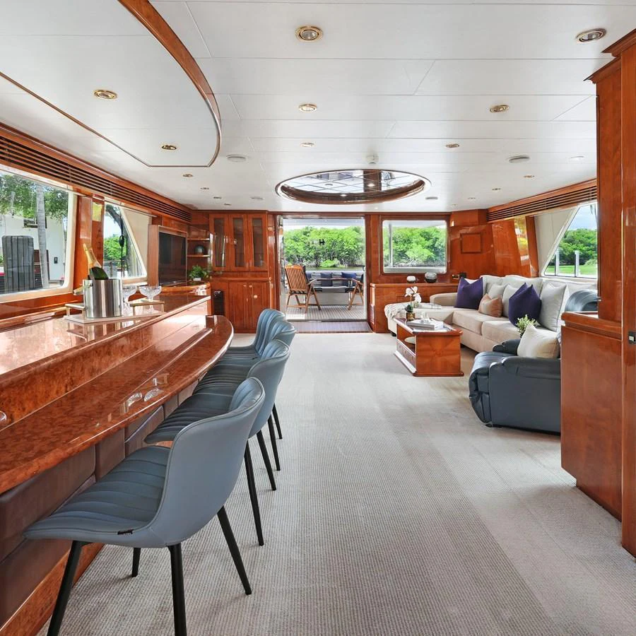 The spacious salon features elegant wood finishes, plush seating, and ample natural light. aboard MILES AWEIGH Yacht for Sale