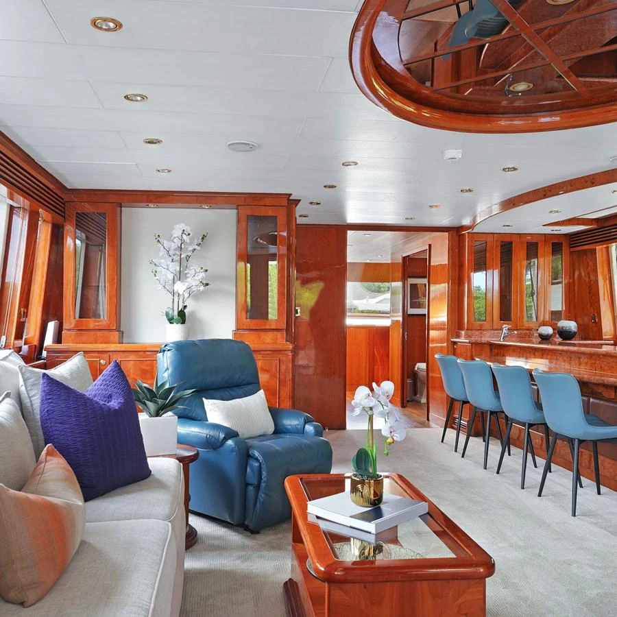 The salon features elegant wood finishes, plush seating, and a stylish bar area. aboard MILES AWEIGH Yacht for Sale