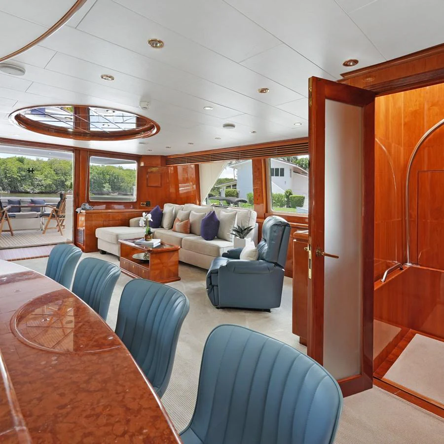 The salon features luxurious seating with elegant wood finishes and ample natural light. aboard MILES AWEIGH Yacht for Sale
