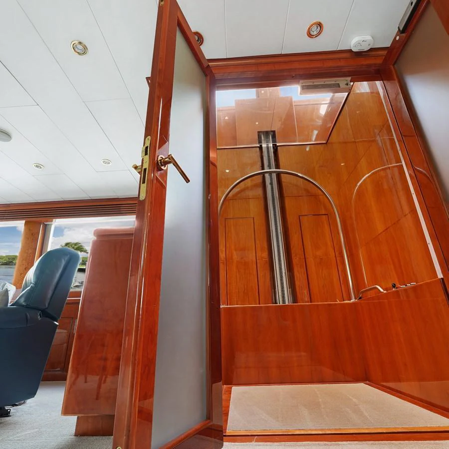 The image showcases a luxurious interior space with polished wood finishes and a glass door. aboard MILES AWEIGH Yacht for Sale