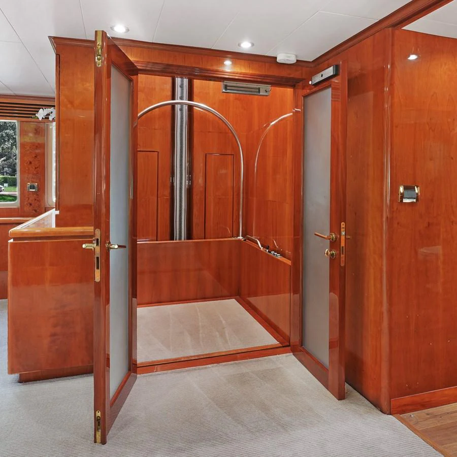 The image showcases a luxurious interior space with rich wooden finishes and frosted glass doors. aboard MILES AWEIGH Yacht for Sale
