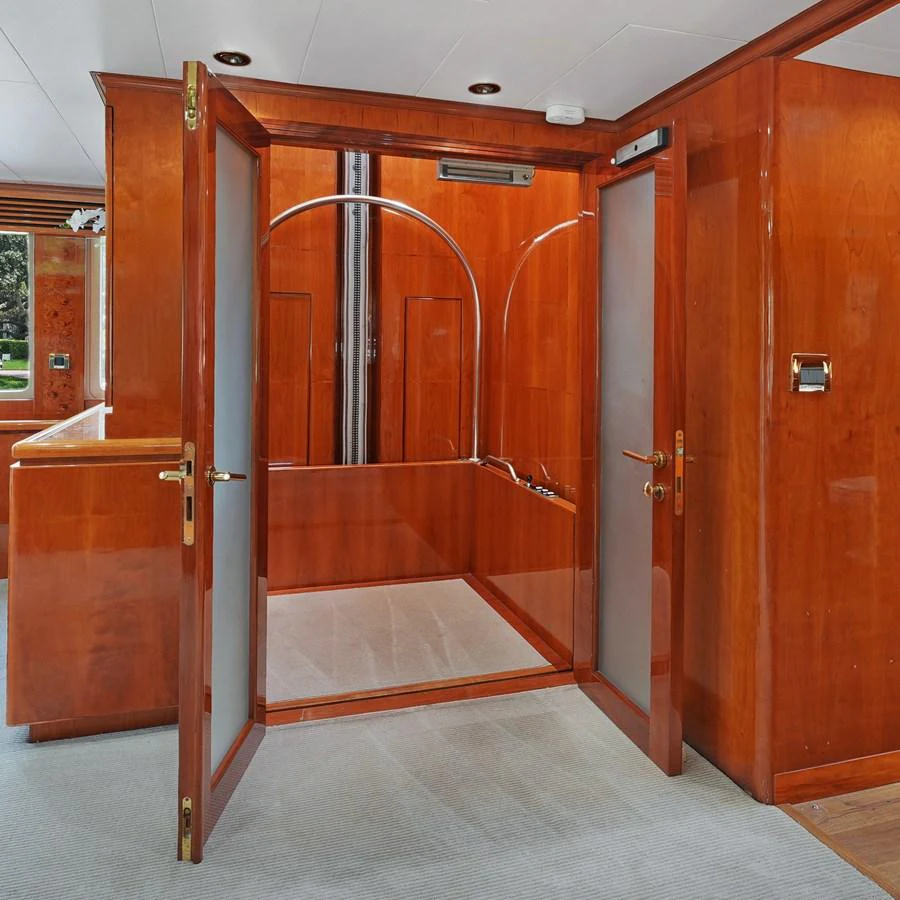 The image showcases a luxurious interior space with rich wooden finishes and frosted glass doors. aboard MILES AWEIGH Yacht for Sale