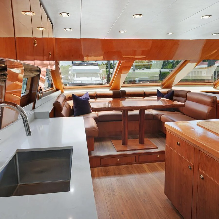 The salon features a cozy seating area with a dining table, surrounded by large windows for ample natural light. aboard MILES AWEIGH Yacht for Sale