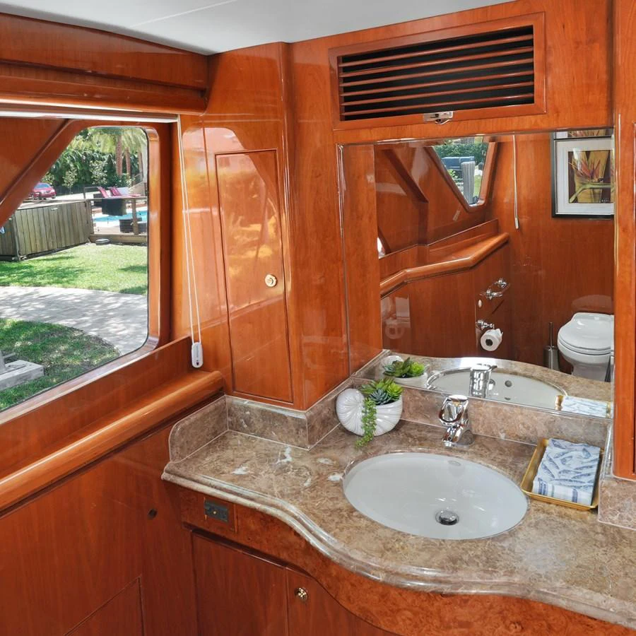 The yacht's bathroom features elegant wood paneling and a polished marble countertop. aboard MILES AWEIGH Yacht for Sale