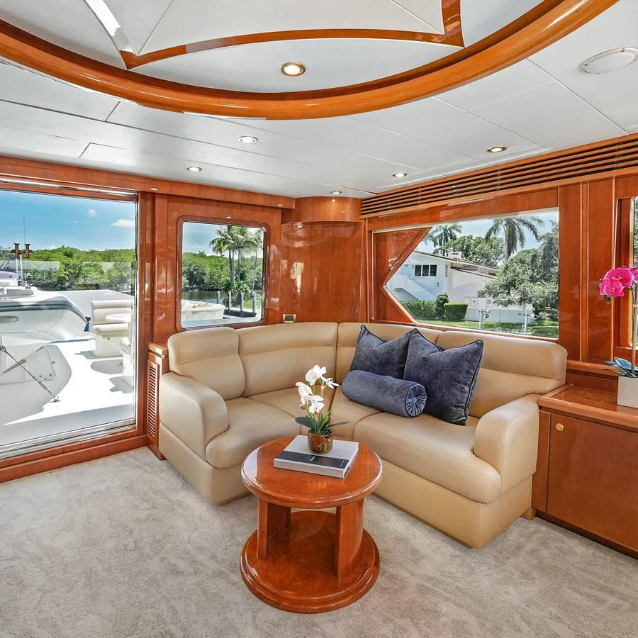 The salon features plush seating with elegant wooden accents and large windows offering scenic views. aboard MILES AWEIGH Yacht for Sale