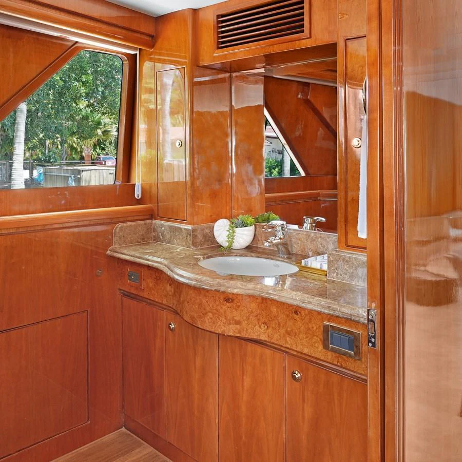 A well-appointed yacht bathroom with elegant wood finishes and a marble countertop. aboard MILES AWEIGH Yacht for Sale