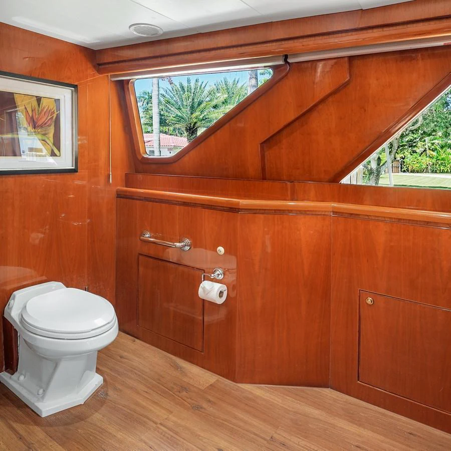 The yacht's head features elegant wood paneling and a large window for natural light. aboard MILES AWEIGH Yacht for Sale