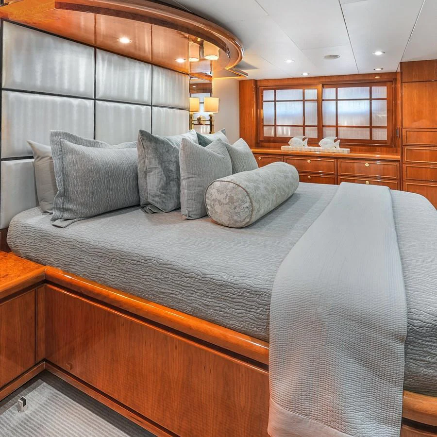 The stateroom features a luxurious bed with plush pillows and elegant wood finishes. aboard MILES AWEIGH Yacht for Sale