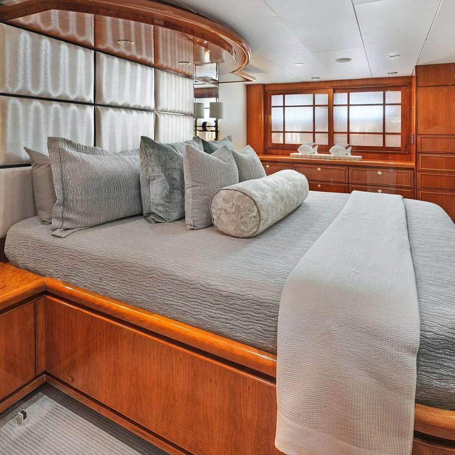 The stateroom features a luxurious bed with plush pillows and elegant wood finishes. aboard MILES AWEIGH Yacht for Sale