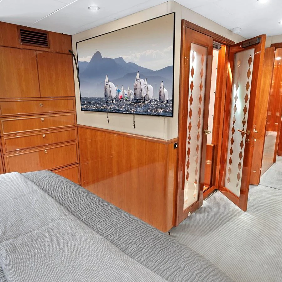 The stateroom features elegant wood paneling and a large flat-screen TV, creating a cozy and sophisticated atmosphere. aboard MILES AWEIGH Yacht for Sale