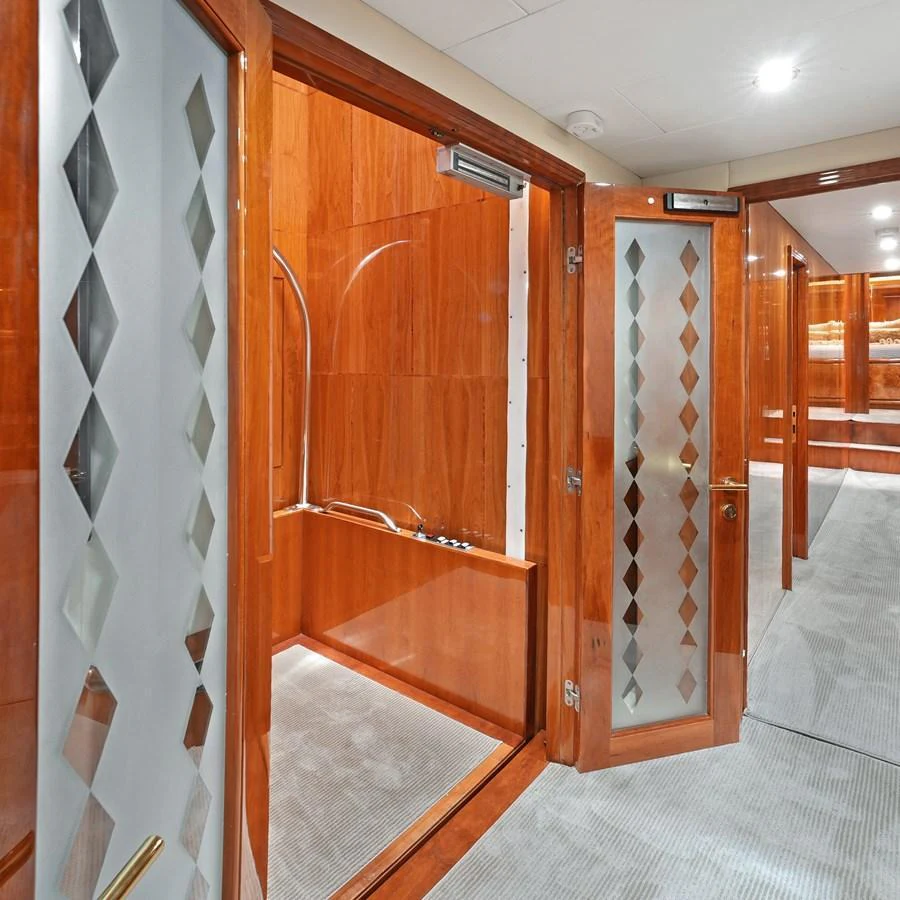 The image showcases a luxurious interior hallway with wooden finishes and frosted glass doors. aboard MILES AWEIGH Yacht for Sale