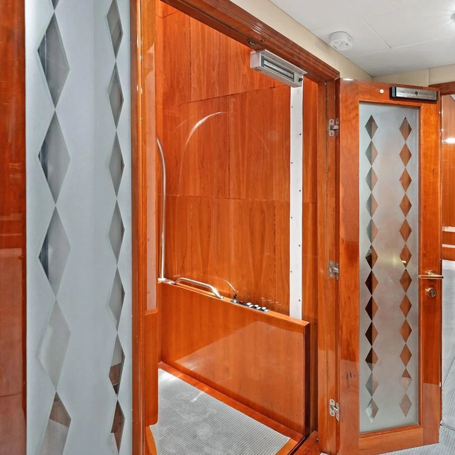 The image showcases a luxurious interior space with polished wooden finishes and frosted glass doors. aboard MILES AWEIGH Yacht for Sale