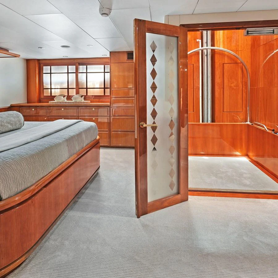 The stateroom features elegant wood paneling and a spacious layout with a comfortable bed and ample storage. aboard MILES AWEIGH Yacht for Sale