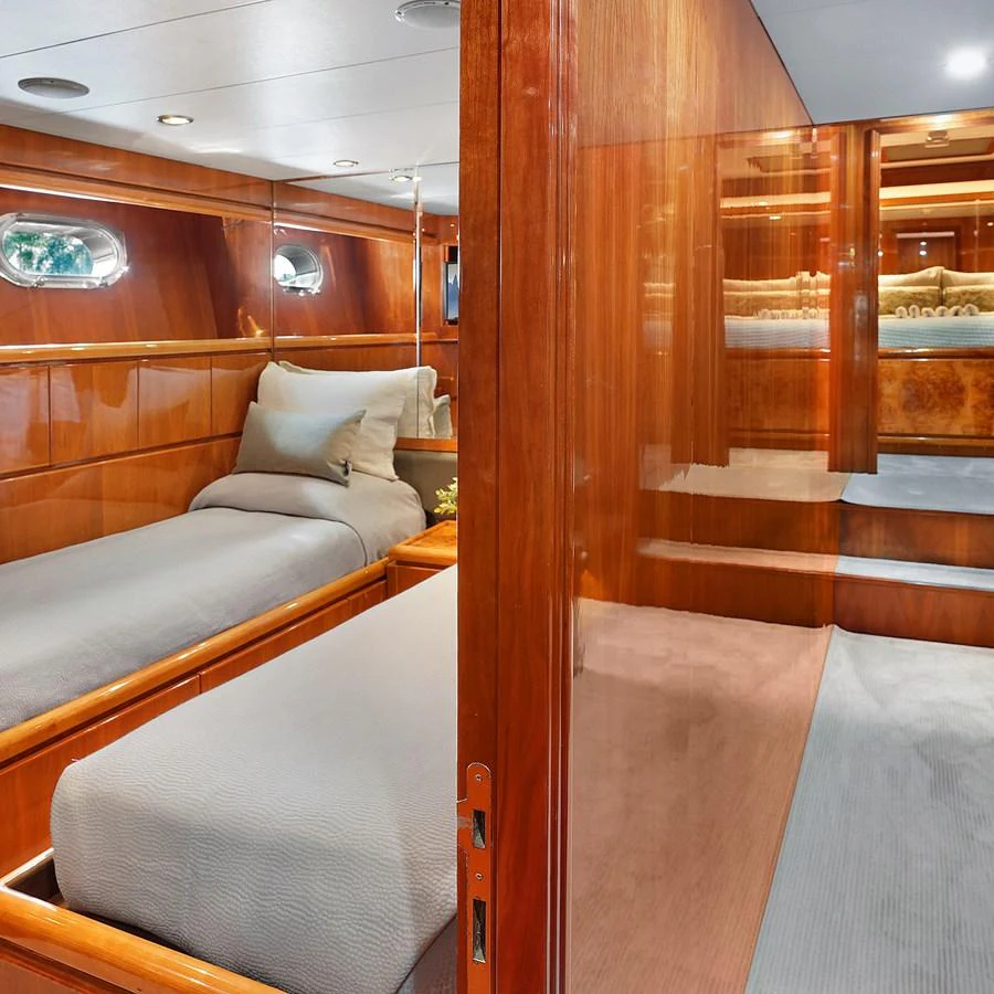The guest stateroom features twin beds with luxurious bedding and rich wood paneling. aboard MILES AWEIGH Yacht for Sale