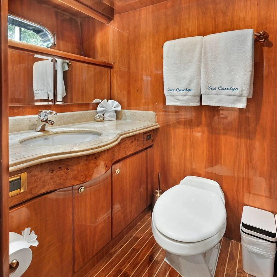 The yacht's bathroom features elegant wood paneling and a sleek marble countertop. aboard MILES AWEIGH Yacht for Sale
