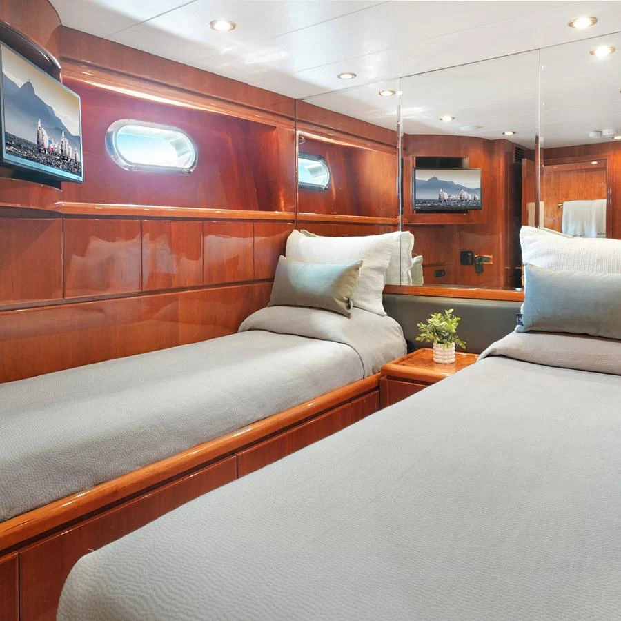 The twin stateroom features elegant wood paneling and comfortable bedding, creating a cozy and inviting atmosphere. aboard MILES AWEIGH Yacht for Sale