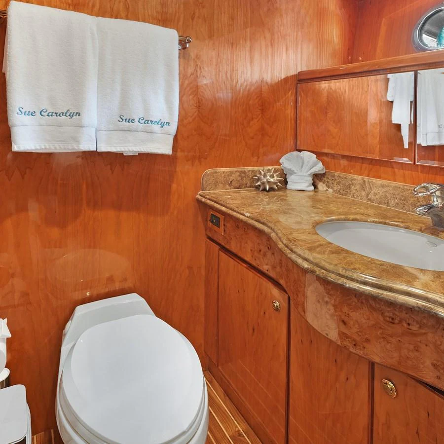 The yacht's bathroom features elegant wood paneling and a marble countertop. aboard MILES AWEIGH Yacht for Sale