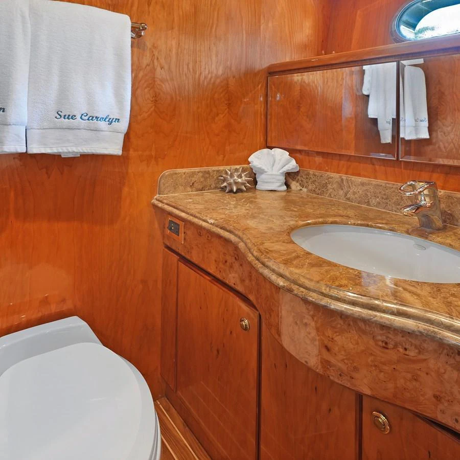 The bathroom features elegant wood paneling and a polished marble countertop. aboard MILES AWEIGH Yacht for Sale