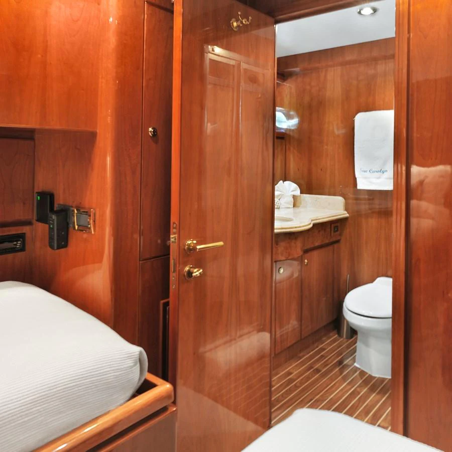 The image showcases a cozy yacht bathroom with wooden finishes and a small adjacent sleeping area. aboard MILES AWEIGH Yacht for Sale