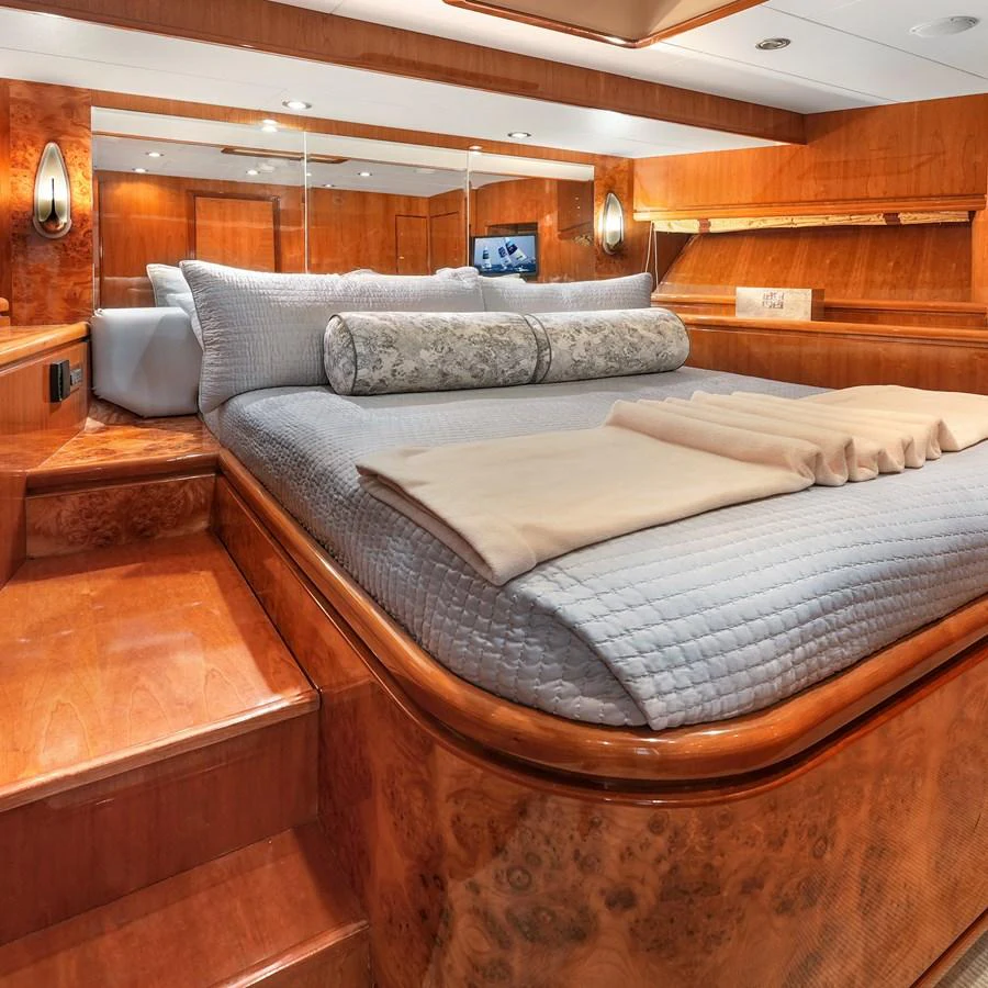 The stateroom features a luxurious bed with elegant wood paneling and ambient lighting. aboard MILES AWEIGH Yacht for Sale