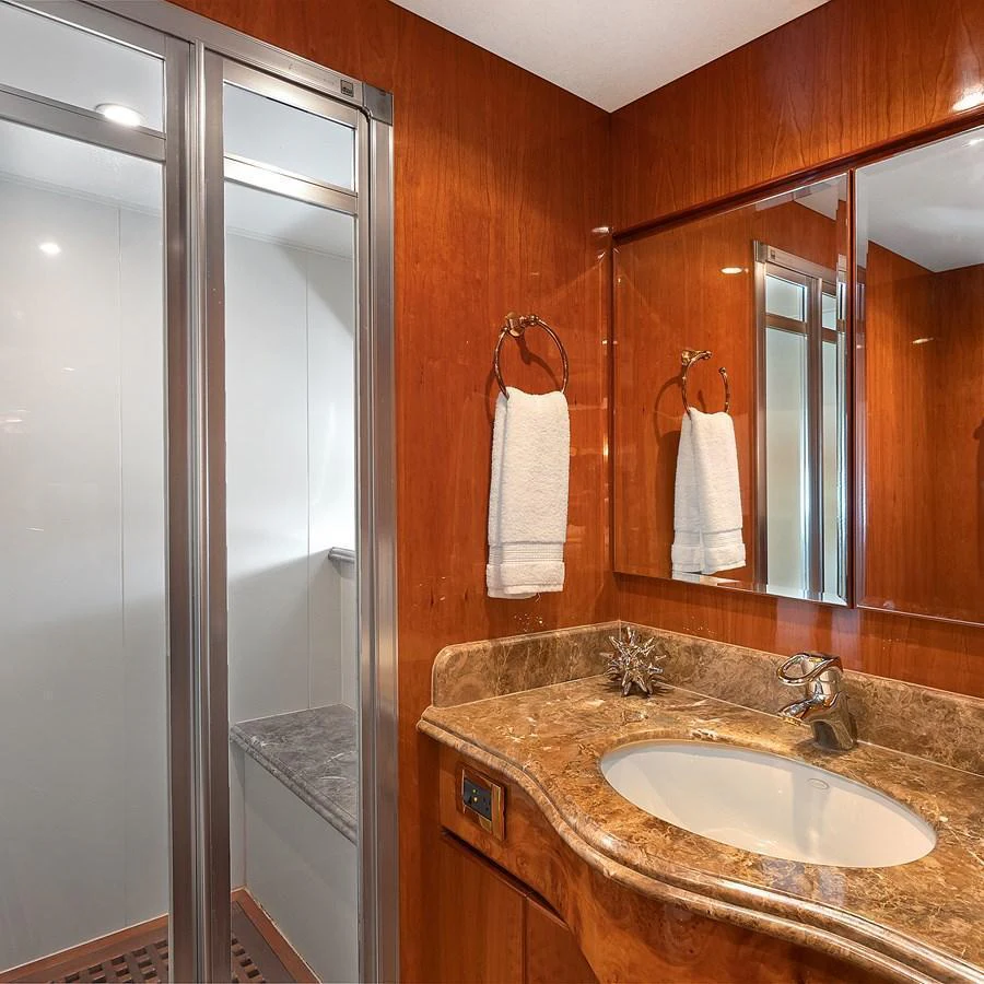 The yacht's bathroom features a sleek design with a marble countertop and a glass-enclosed shower. aboard MILES AWEIGH Yacht for Sale