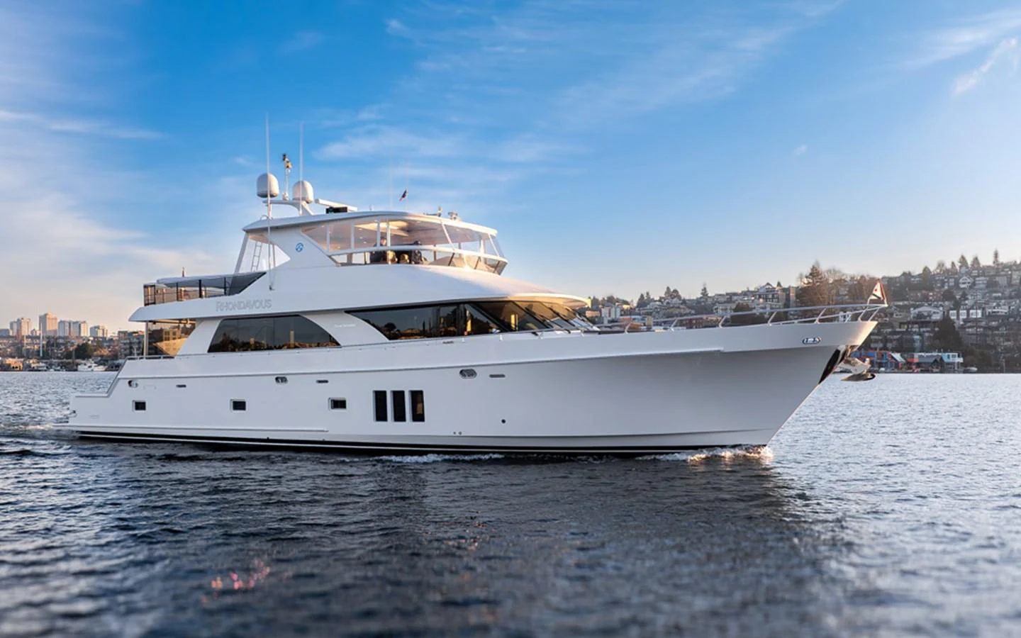A sleek and modern yacht cruises gracefully on calm waters under a clear blue sky. aboard RHONDAVOUS Yacht for Sale