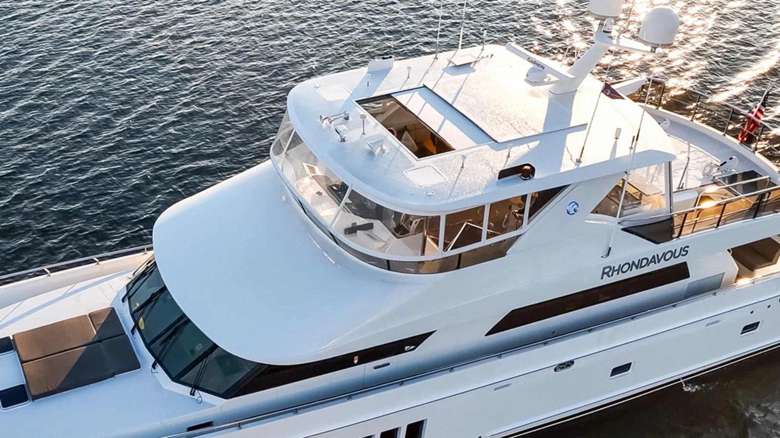 A sleek and modern yacht glides gracefully on the water, showcasing its elegant design and spacious upper deck. aboard RHONDAVOUS Yacht for Sale