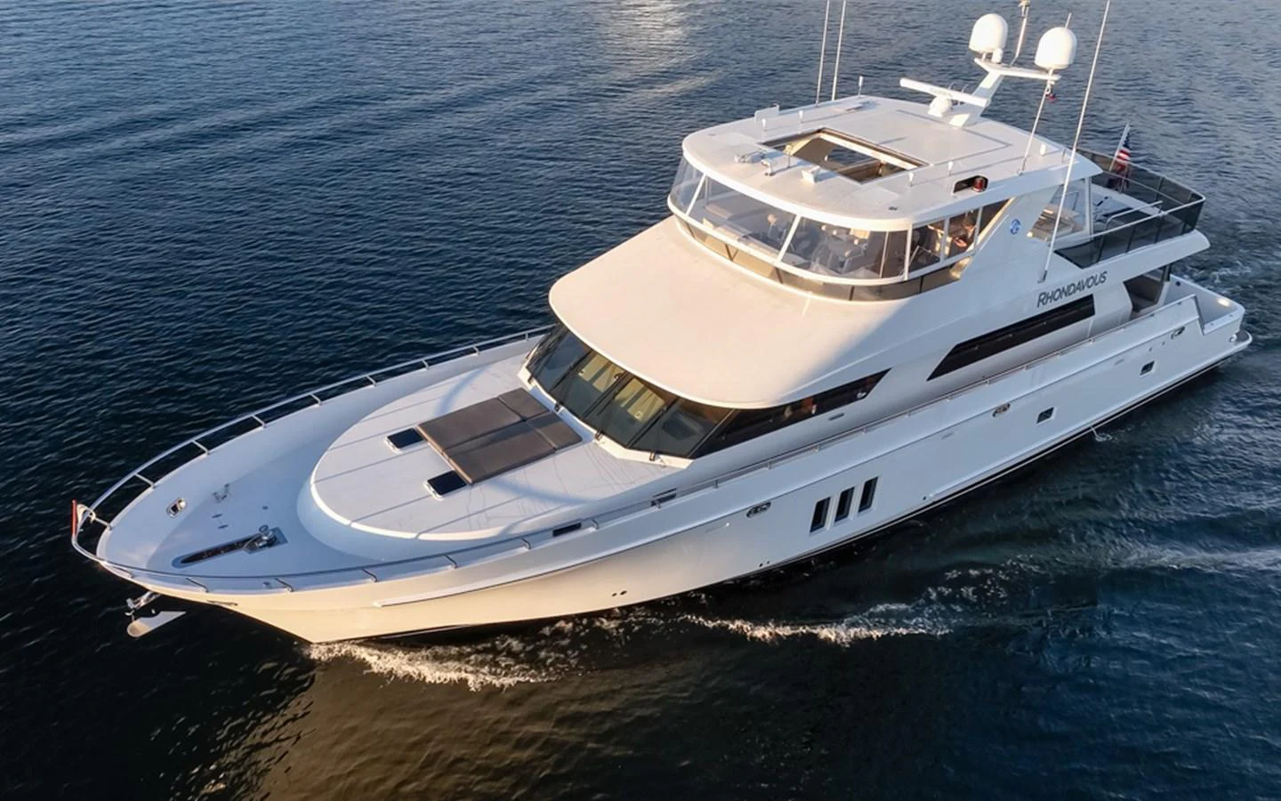 A sleek, modern yacht glides gracefully across calm waters, showcasing its elegant design and spacious decks. aboard RHONDAVOUS Yacht for Sale