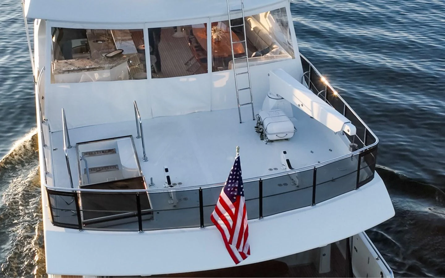 The yacht's aft deck offers a spacious area with seating and an American flag proudly displayed. aboard RHONDAVOUS Yacht for Sale