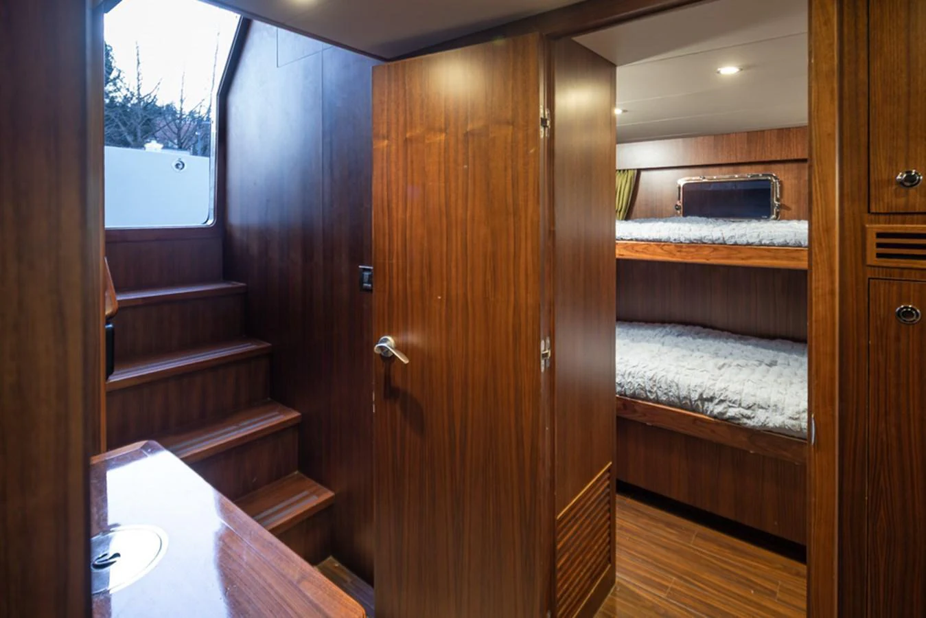 The image showcases a cozy cabin with wooden finishes and bunk beds. aboard RHONDAVOUS Yacht for Sale