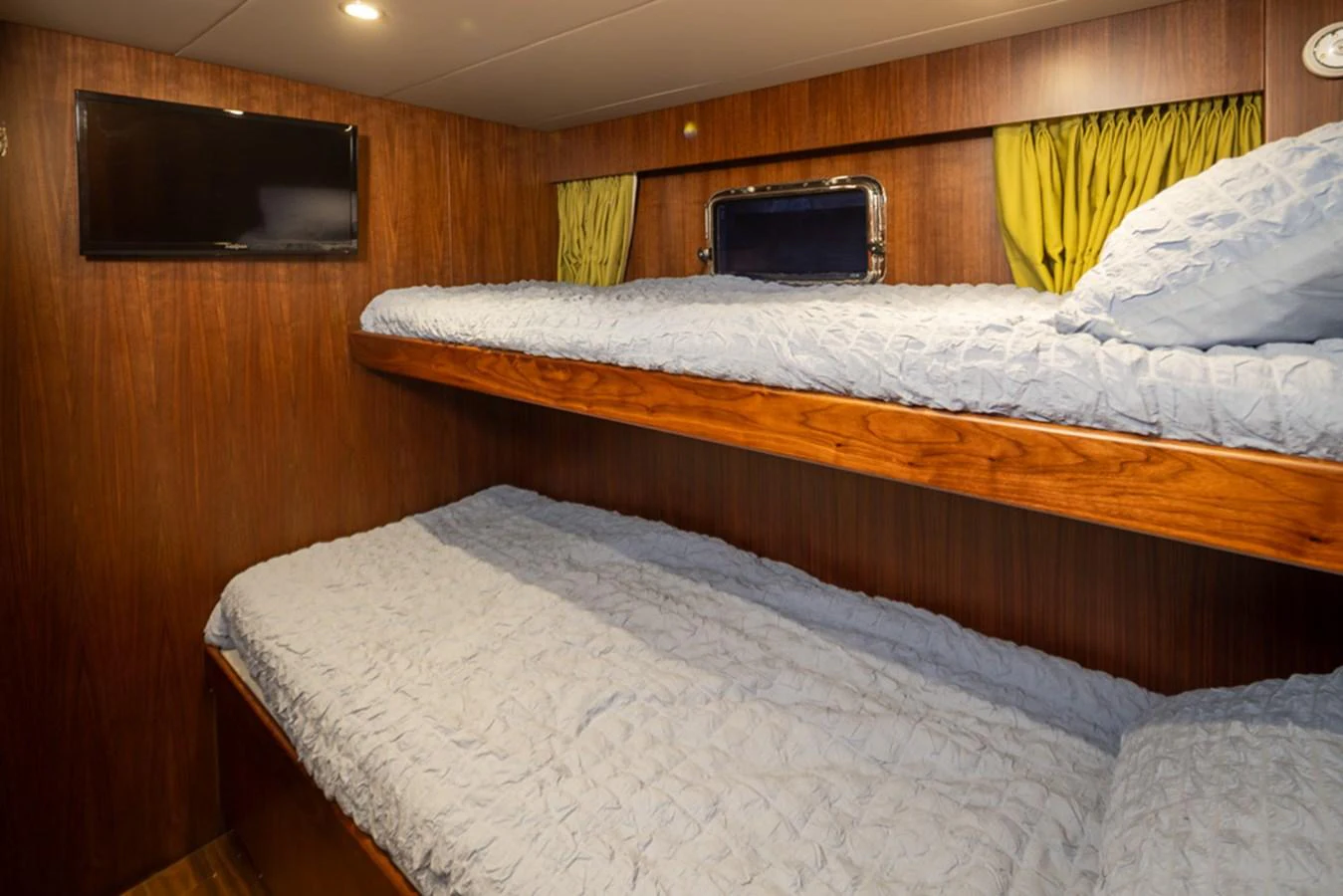 The cozy bunk cabin features wooden paneling and comfortable bedding. aboard RHONDAVOUS Yacht for Sale