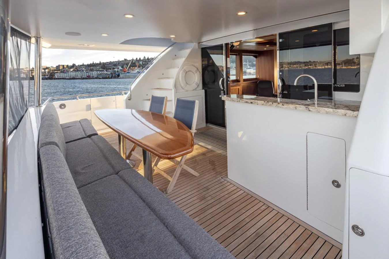 The aft deck features a comfortable seating area with a wooden table, perfect for alfresco dining. aboard RHONDAVOUS Yacht for Sale