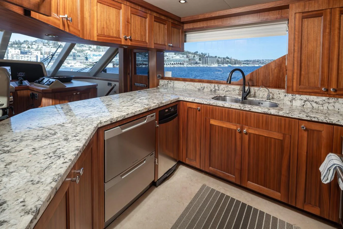 The galley features rich wooden cabinetry, modern appliances, and a scenic view through large windows. aboard RHONDAVOUS Yacht for Sale