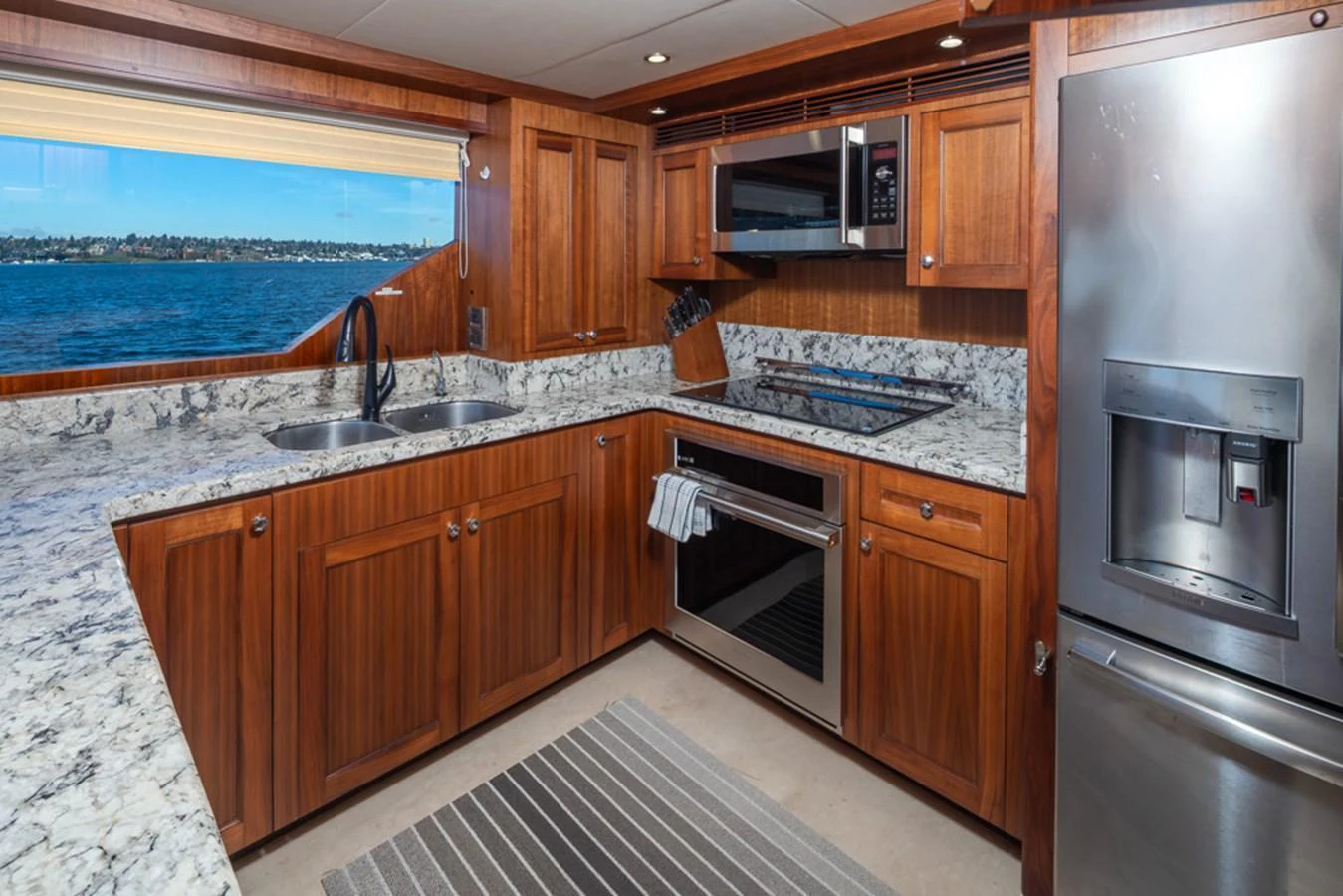 The galley features rich wood cabinetry, modern appliances, and a scenic view through the window. aboard RHONDAVOUS Yacht for Sale