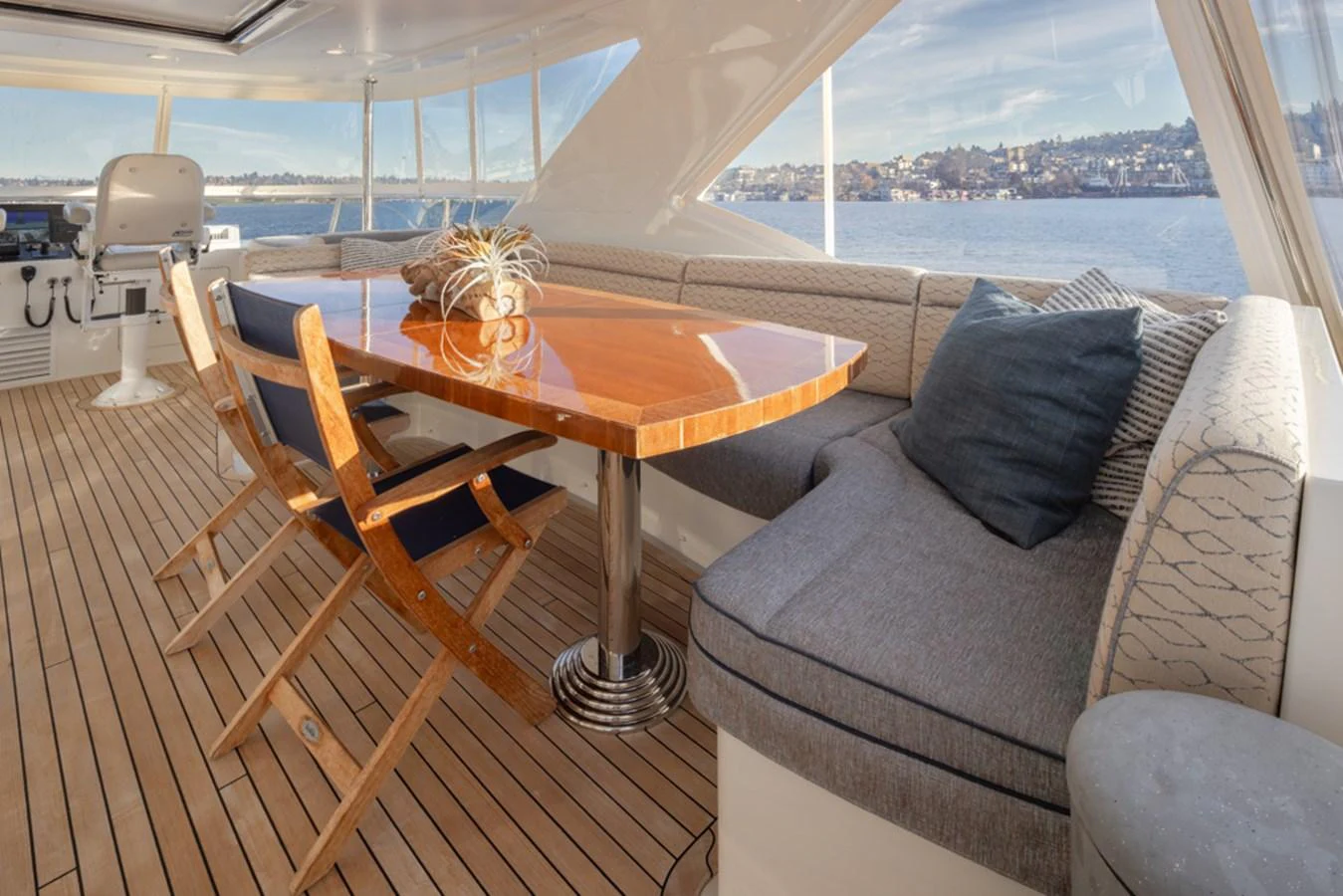 The aft deck features a stylish dining area with a polished wooden table and comfortable seating, offering stunning views of the water. aboard RHONDAVOUS Yacht for Sale