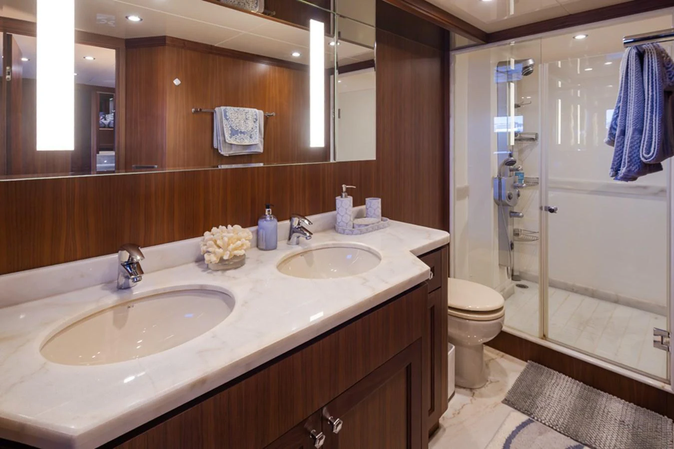 The yacht's bathroom features a double sink vanity with a marble countertop and a spacious glass-enclosed shower. aboard RHONDAVOUS Yacht for Sale
