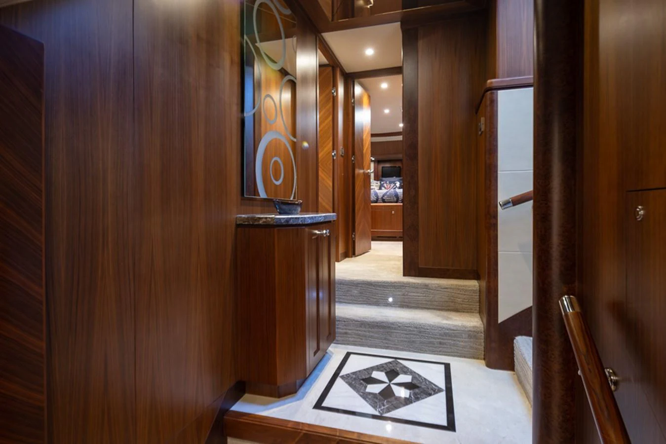 The yacht's interior features elegant wood paneling and a stylishly designed hallway with a decorative floor inlay. aboard RHONDAVOUS Yacht for Sale