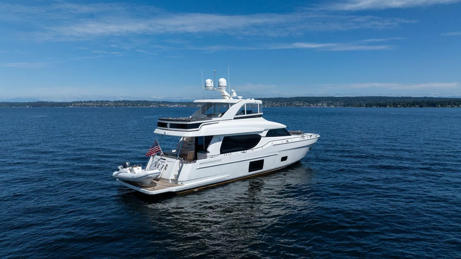 A sleek and modern yacht cruising on calm waters under a clear blue sky. aboard SUB-PAR Yacht for Sale