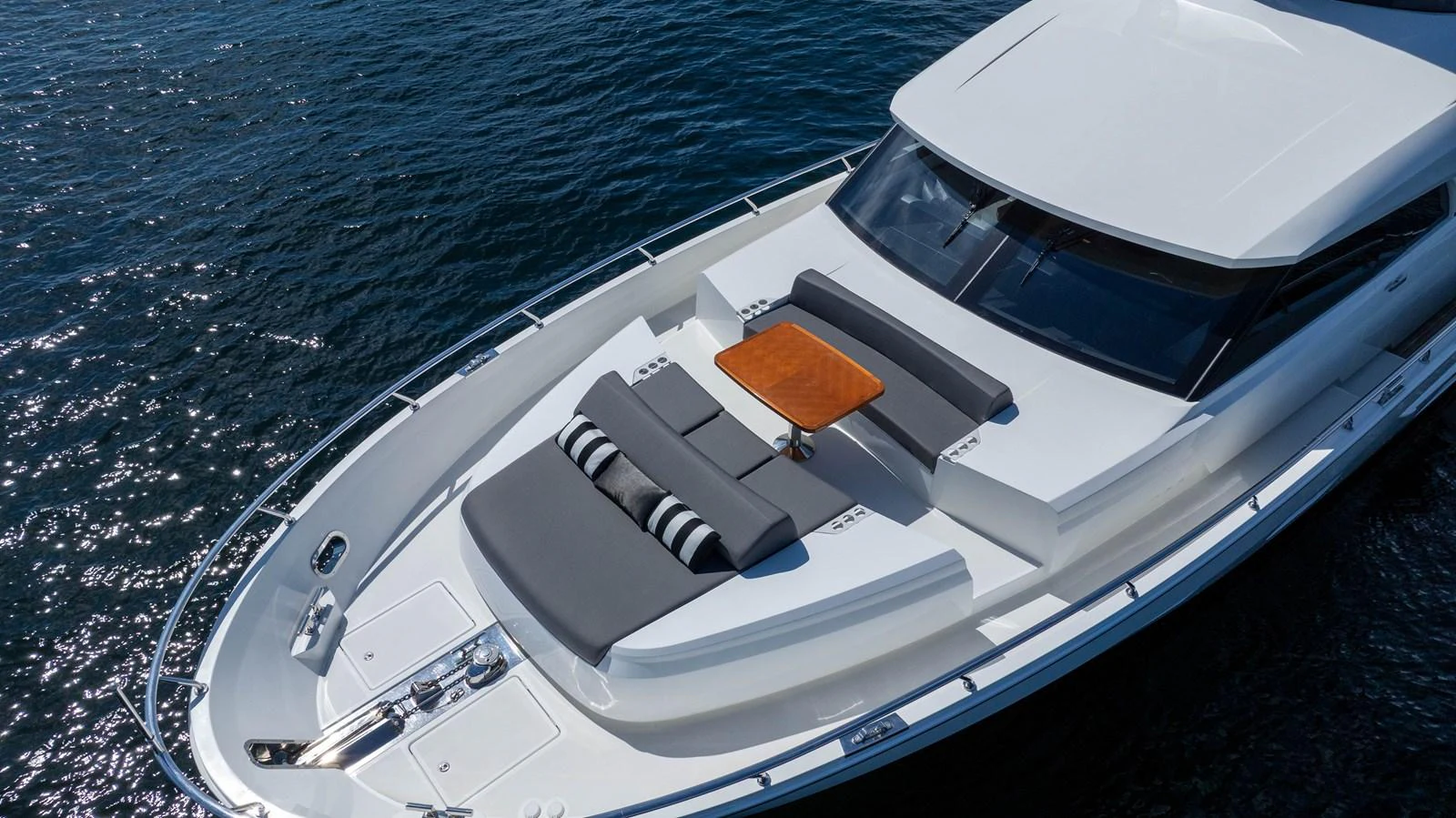 The yacht's foredeck features a stylish seating area with a wooden table, perfect for relaxation and socializing. aboard SUB-PAR Yacht for Sale