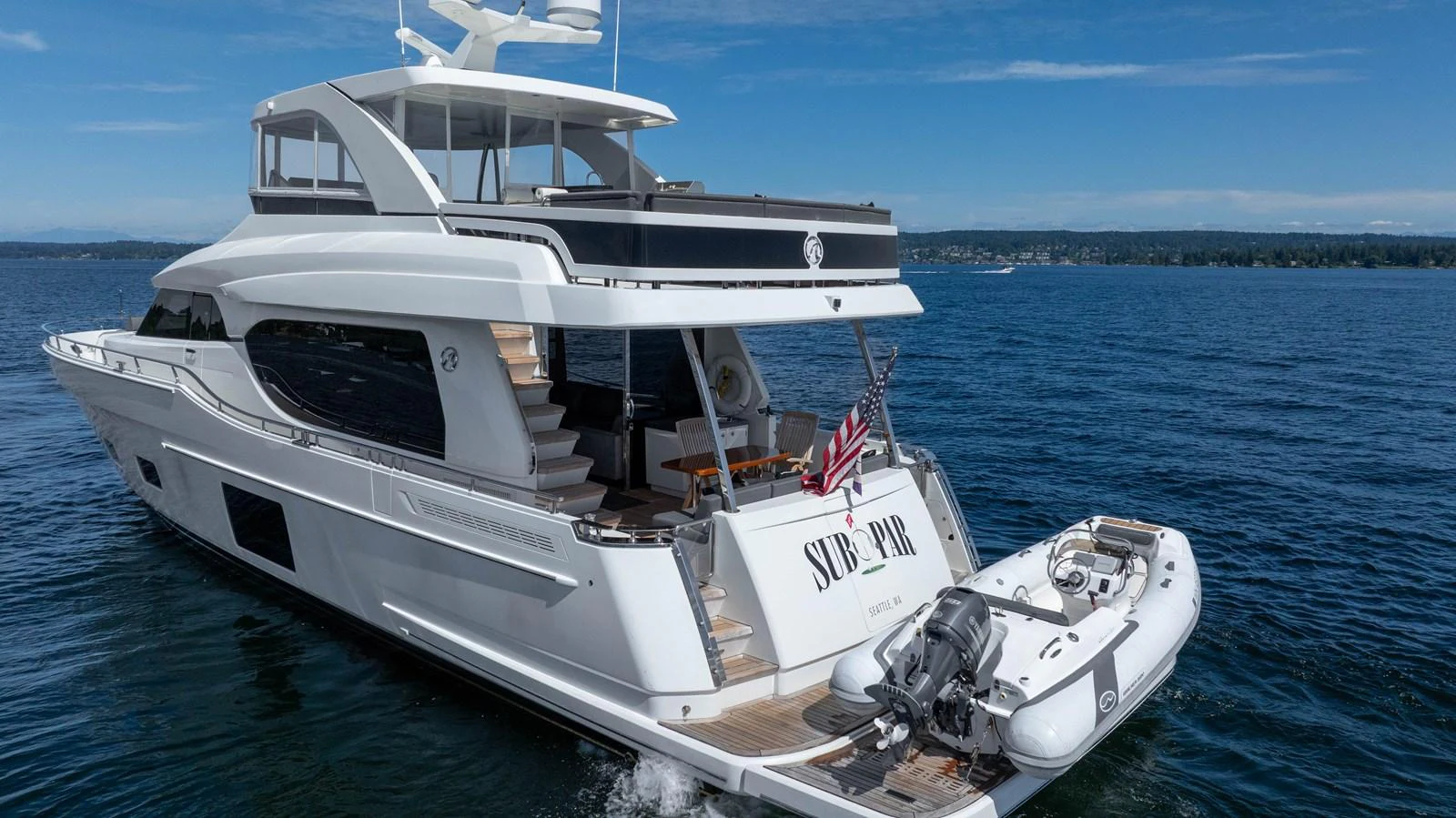 A sleek yacht cruising on calm waters with a tender attached at the stern. aboard SUB-PAR Yacht for Sale