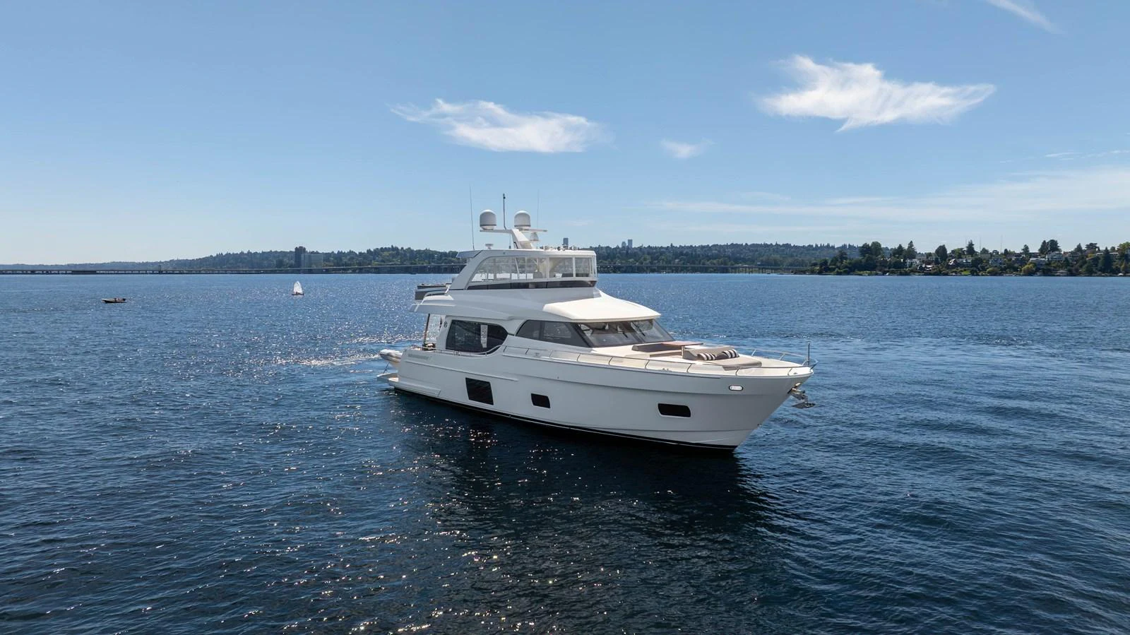 A sleek white yacht cruises gracefully on calm blue waters under a clear sky. aboard SUB-PAR Yacht for Sale