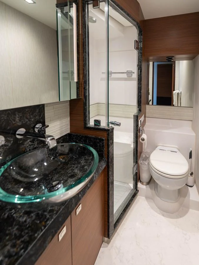 A modern yacht bathroom featuring a glass sink and enclosed shower. aboard SUB-PAR Yacht for Sale