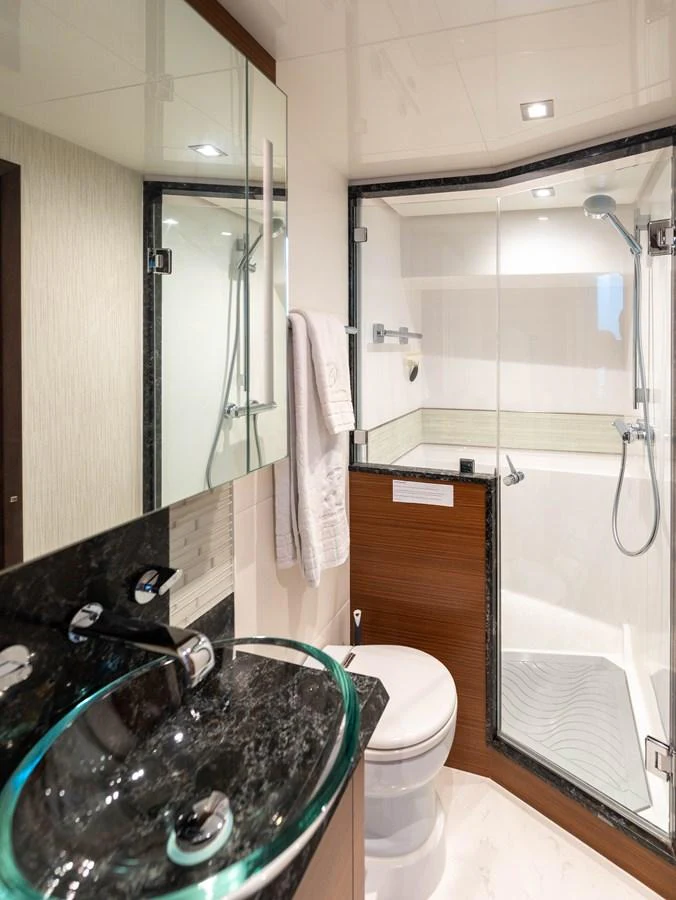 A modern yacht bathroom featuring a glass-enclosed shower, sleek sink, and elegant fixtures. aboard SUB-PAR Yacht for Sale