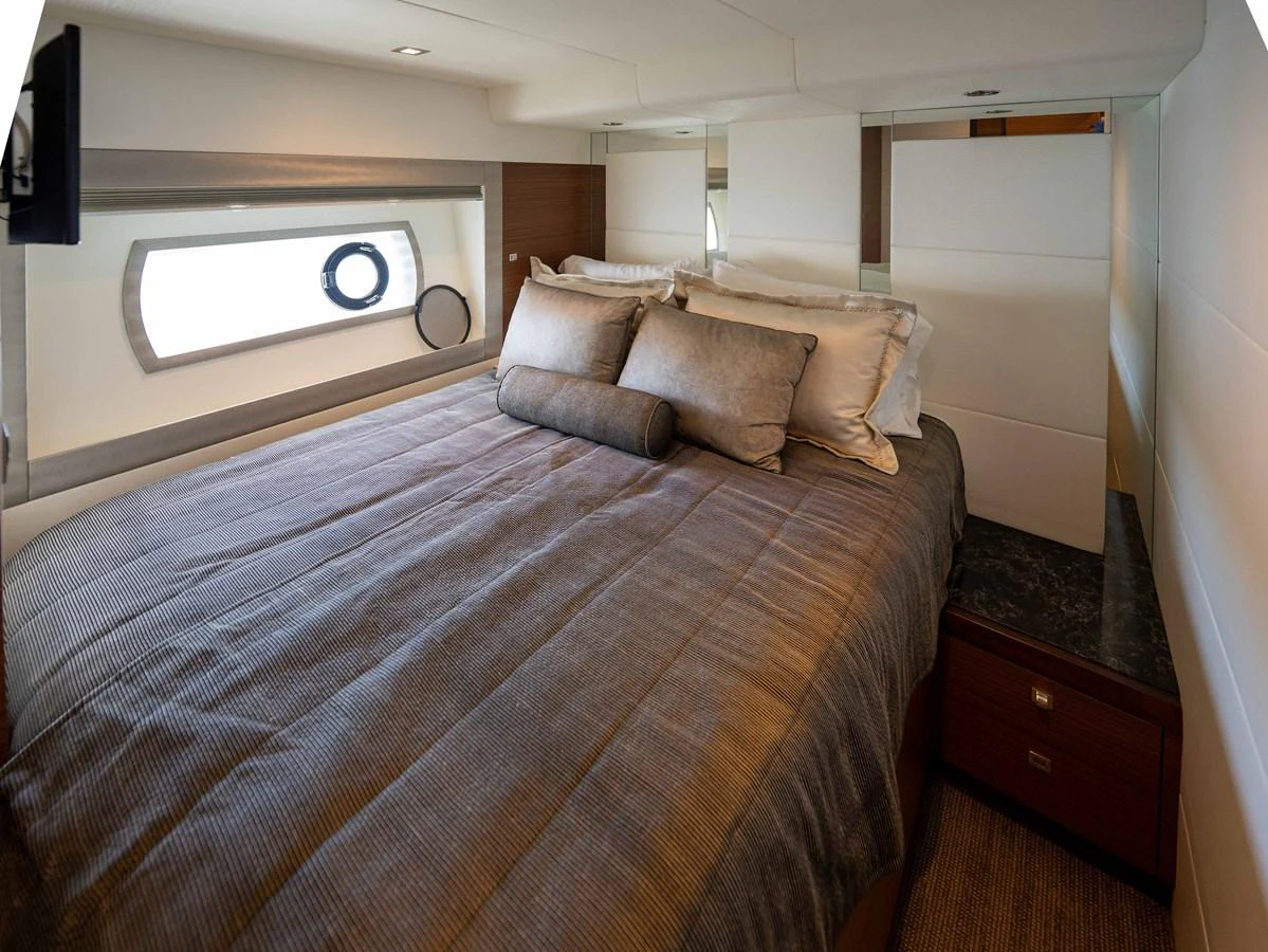 The stateroom features a plush bed with elegant bedding and ample natural light from the side window. aboard SUB-PAR Yacht for Sale