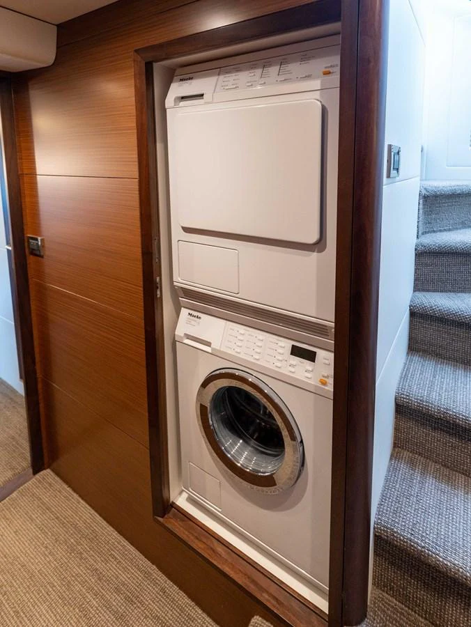The yacht features a convenient laundry area with a stacked washer and dryer. aboard SUB-PAR Yacht for Sale