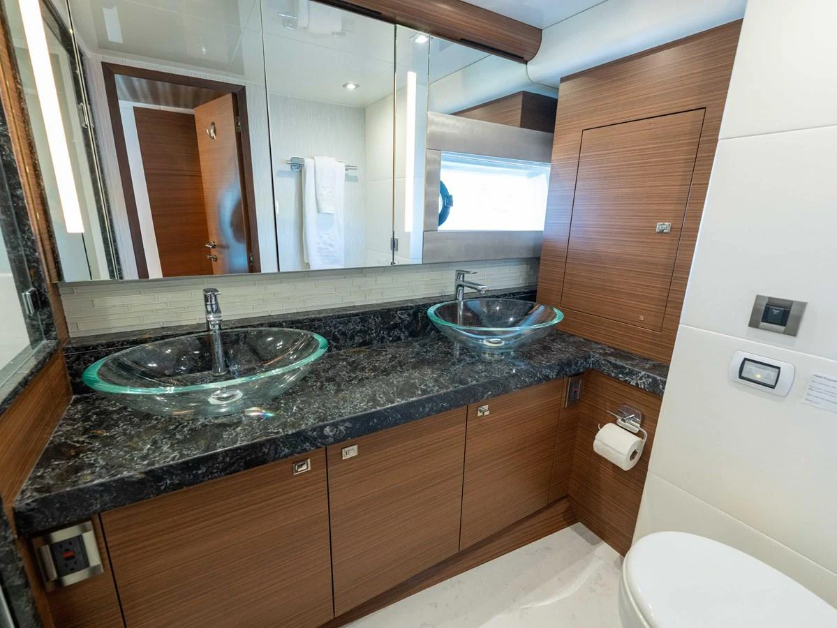 The yacht's bathroom features dual glass sinks and elegant wood cabinetry. aboard SUB-PAR Yacht for Sale