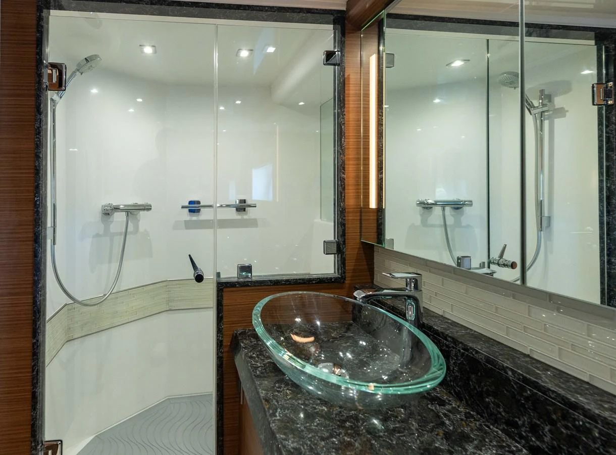 A modern yacht bathroom featuring a glass sink and spacious shower area. aboard SUB-PAR Yacht for Sale