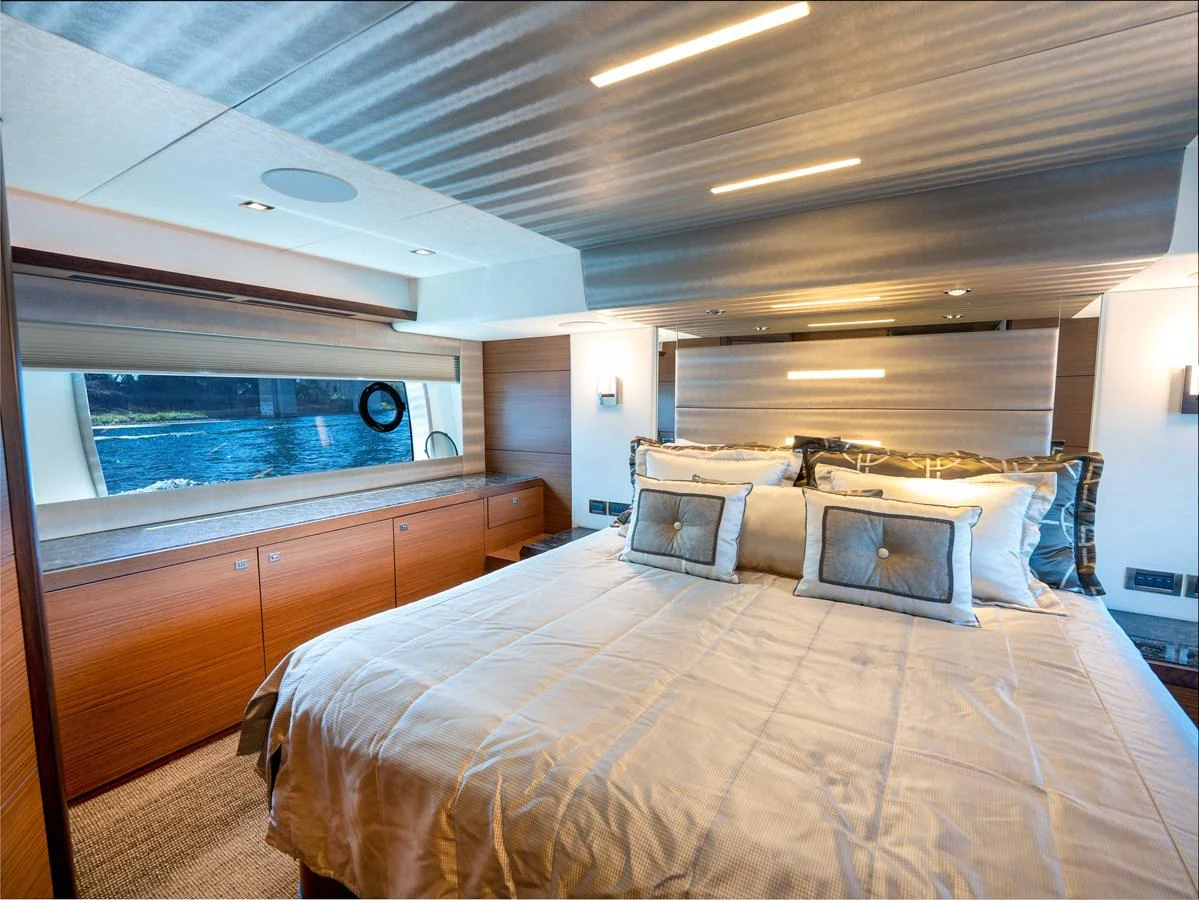 The stateroom features a luxurious bed with elegant bedding and ample natural light from the large window. aboard SUB-PAR Yacht for Sale