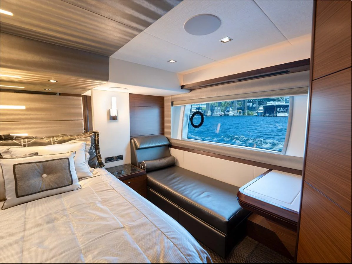 A luxurious stateroom featuring a large window with a view of the water, a comfortable bed, and a chaise lounge. aboard SUB-PAR Yacht for Sale